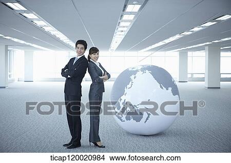 a businessman and woman standing back to back next to a huge globe View Large Photo Image Picture - a businessman and woman standing back to back next to a huge globe. Fotosearch
