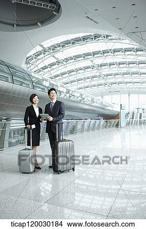 Picture - a businessman and woman standing with luggage in Incheon airport. Fotosearch