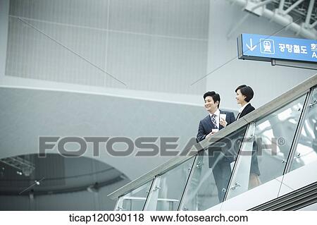 Stock Photo - a businessman and woman talking in Incheon airport. Fotosearch