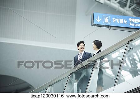 Stock Photograph - a businessman and woman talking in Incheon airport. Fotosearch
