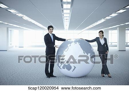 a businessman and woman touching a huge globe in an empty room View Large Photo Image Picture - a businessman and woman touching a huge globe in an empty room. Fotosearch