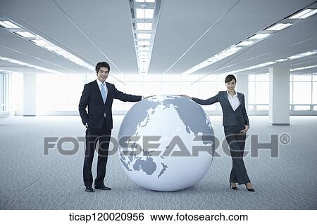 a businessman and woman touching a huge globe in an empty room View Large Photo Image Stock Photograph - a businessman and woman touching a huge globe in an empty room. Fotosearch