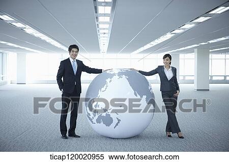 a businessman and woman touching a huge globe in an empty room View Large Photo Image Stock Photography - a businessman and woman touching a huge globe in an empty room. Fotosearch