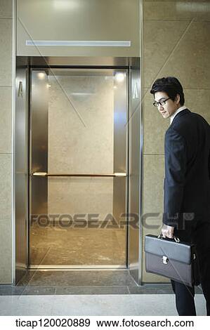a businessman facing back at camera in front of an empty elevator View Large Photo Image Stock Photo - a businessman facing back at camera in front of an empty elevator . Fotosearch