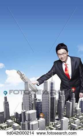 Picture - a businessman holding a building . Fotosearch