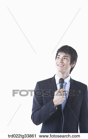 Stock Image - a businessman in a black suit holding a microphone looking up. Fotosearch