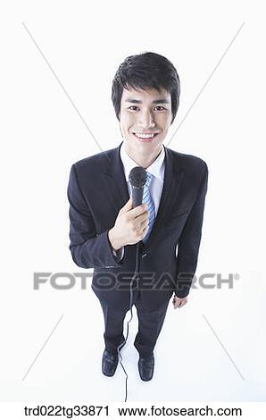 a businessman in a black suit holding a microphone looking up to camera View Large Photo Image Stock Image - a businessman in a black suit holding a microphone looking up to camera. Fotosearch