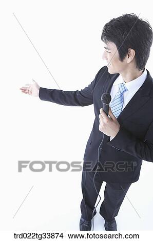 a businessman in a black suit explaining something using microphone View Large Photo Image Picture - a businessman in a black suit explaining something using microphone . Fotosearch