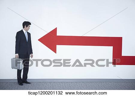 a businessman looking at an arrow on the wall View Large Photo Image Stock Image - a businessman looking at an arrow on the wall. Fotosearch