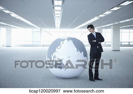 a businessman looking into a globe with arms crossed View Large Photo Image Stock Photo - a businessman looking into a globe with arms crossed. Fotosearch