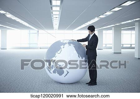 a businessman looking into a huge globe in an empty room View Large Photo Image Stock Image - a businessman looking into a huge globe in an empty room. Fotosearch
