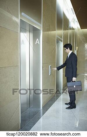 a businessman pressing button for an elevator in a office building View Large Photo Image Stock Image - a businessman pressing button for an elevator in a office building. Fotosearch
