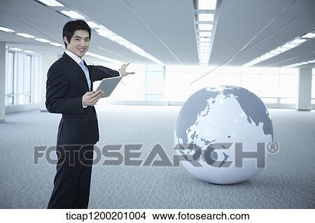a businessman showing a globe in an empty room View Large Photo Image Picture - a businessman showing a globe in an empty room. Fotosearch