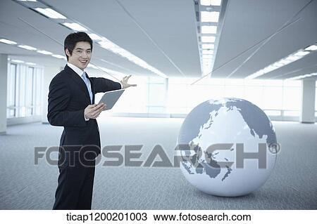 a businessman showing a globe in an empty room View Large Photo Image Stock Image - a businessman showing a globe in an empty room. Fotosearch