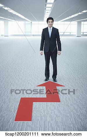 Stock Image - a businessman standing in the end of an arrow in an empty room. Fotosearch