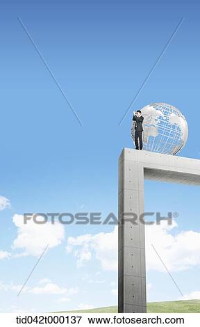 a businessman standing on top of a gate with a globe View Large Photo Image Stock Photo - a businessman standing on top of a gate with a globe. Fotosearch