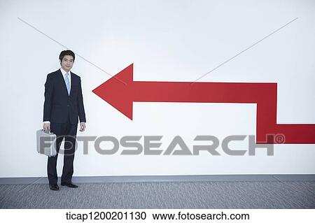 a businessman standing to an arrow on the wall View Large Photo Image Stock Image - a businessman standing to an arrow on the wall. Fotosearch