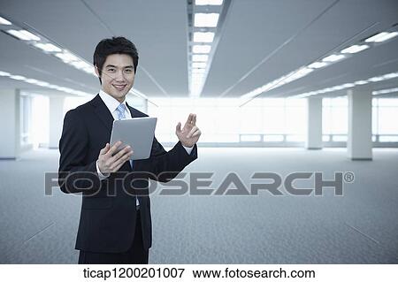 a businessman standing with tablet PC in an empty room View Large Photo Image Stock Photo - a businessman standing with tablet PC in an empty room. Fotosearch