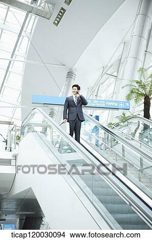 a businessman talking on the phone in escalator of Incheon airport View Large Photo Image Picture - a businessman talking on the phone in escalator of Incheon airport. Fotosearch