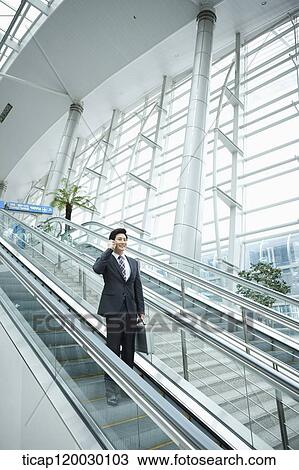 a businessman talking on the phone in escalator of Incheon airport View Large Photo Image Stock Image - a businessman talking on the phone in escalator of Incheon airport. Fotosearch