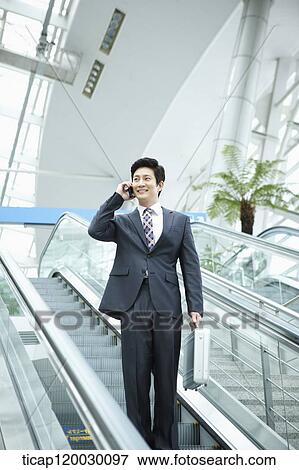a businessman talking on the phone in escalator of Incheon airport View Large Photo Image Stock Photo - a businessman talking on the phone in escalator of Incheon airport. Fotosearch