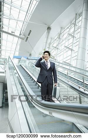 a businessman talking on the phone in escalator of Incheon airport View Large Photo Image Stock Photo - a businessman talking on the phone in escalator of Incheon airport. Fotosearch