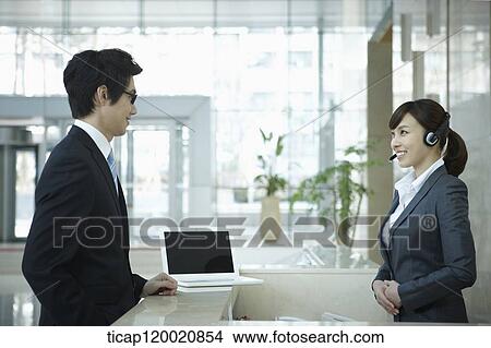a businessman talking to a help desk in a office building View Large Photo Image Picture - a businessman talking to a help desk in a office building . Fotosearch