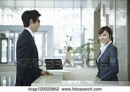 a businessman talking to a help desk in a office building View Large Photo Image Stock Image - a businessman talking to a help desk in a office building . Fotosearch