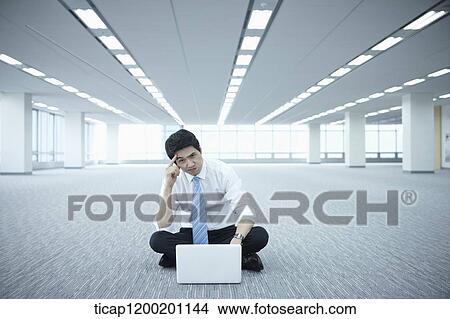 a businessman using laptop on the floor of an empty room View Large Photo Image Picture - a businessman using laptop on the floor of an empty room. Fotosearch