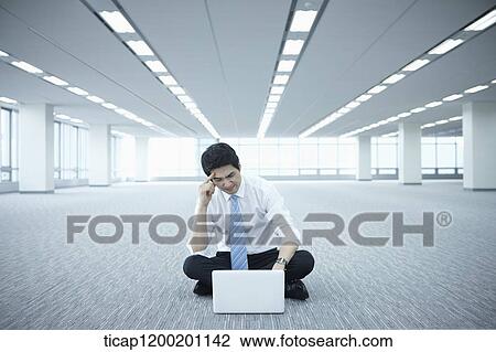a businessman using laptop on the floor of an empty room View Large Photo Image Stock Image - a businessman using laptop on the floor of an empty room. Fotosearch