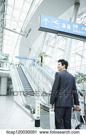 Stock Image - a businessman watching with a luggage in a Incheon airport . Fotosearch