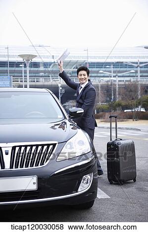 a businessman with a luggage waving hand while opening a door of a car View Large Photo Image Stock Photo - a businessman with a luggage waving hand while opening a door of a car. Fotosearch