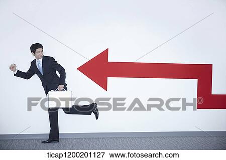 a businessman with running pose next to an arrow on the wall View Large Photo Image Stock Photo - a businessman with running pose next to an arrow on the wall. Fotosearch