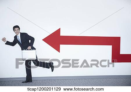 a businessman with running pose next to an arrow on the wall View Large Photo Image Stock Photo - a businessman with running pose next to an arrow on the wall. Fotosearch
