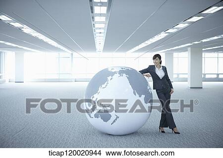 a businesswoman leaning on a huge globe in an empty room View Large Photo Image Picture - a businesswoman leaning on a huge globe in an empty room. Fotosearch