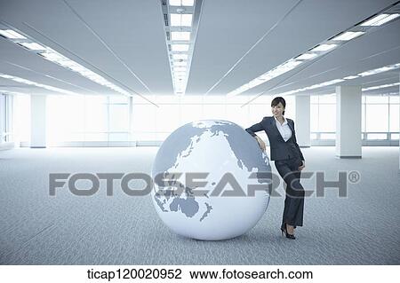 a businesswoman leaning on a huge globe in an empty room View Large Photo Image Stock Image - a businesswoman leaning on a huge globe in an empty room. Fotosearch