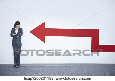 a businesswoman looking at an arrow on the wall while leaning on the wall View Large Photo Image Stock Image - a businesswoman looking at an arrow on the wall while leaning on the wall. Fotosearch