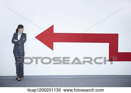 a businesswoman looking at an arrow on the wall while leaning on the wall View Large Photo Image Stock Photography - a businesswoman looking at an arrow on the wall while leaning on the wall. Fotosearch