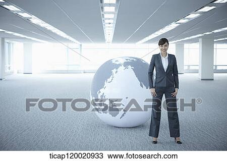 a businesswoman standing in an empty room in front of a huge globe View Large Photo Image Stock Image - a businesswoman standing in an empty room in front of a huge globe. Fotosearch