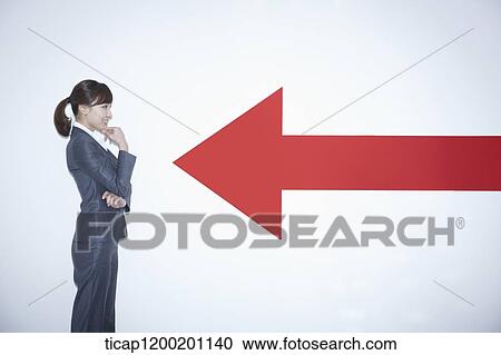 Stock Image - a businesswoman standing towards arrow on the wall. Fotosearch