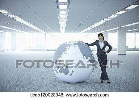 a businesswoman touching a huge globe in an empty room View Large Photo Image Stock Photo - a businesswoman touching a huge globe in an empty room. Fotosearch