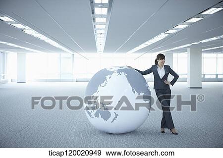 a businesswoman touching a huge globe in an empty room View Large Photo Image Stock Photo - a businesswoman touching a huge globe in an empty room. Fotosearch