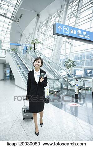 Stock Image - a businesswoman walking in a Incheon airport with a luggage. Fotosearch
