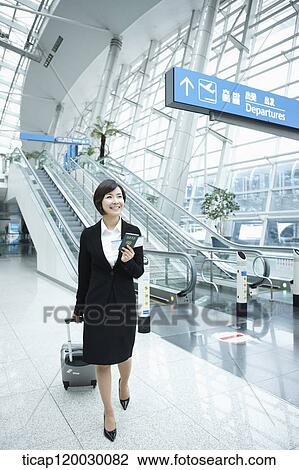 Stock Image - a businesswoman walking in a Incheon airport with a luggage. Fotosearch