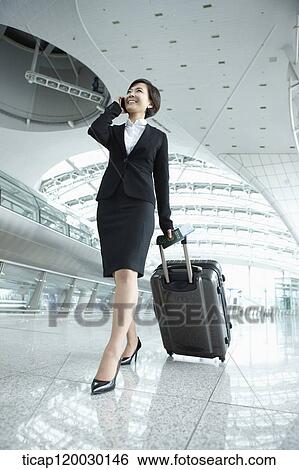 Stock Photograph - a businesswoman walking while talking on the phone in Incheon airport. Fotosearch