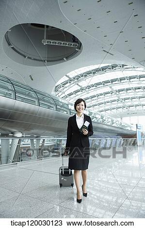 Stock Image - a businesswoman walking with luggage in Incheon airport. Fotosearch