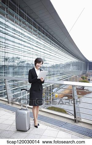 a businesswoman with a luggage and a tabletPC standing in Incheon airport View Large Photo Image Picture - a businesswoman with a luggage and a tabletPC standing in Incheon airport. Fotosearch