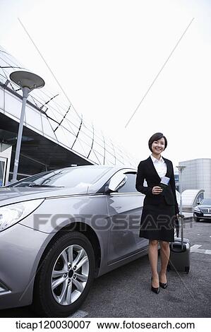 a businesswoman with a luggage and a passport standing next to a car View Large Photo Image Stock Photo - a businesswoman with a luggage and a passport standing next to a car. Fotosearch