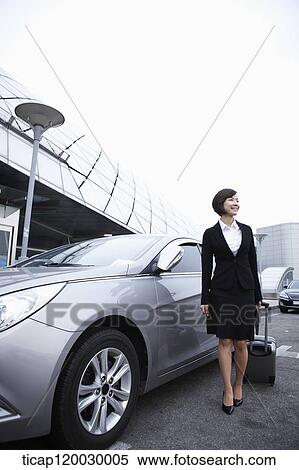 a businesswoman with a luggage standing next to a car View Large Photo Image Stock Photography - a businesswoman with a luggage standing next to a car. Fotosearch