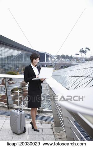 a businesswoman with a luggage working on laptop in Incheon airport View Large Photo Image Stock Photo - a businesswoman with a luggage working on laptop in Incheon airport. Fotosearch
